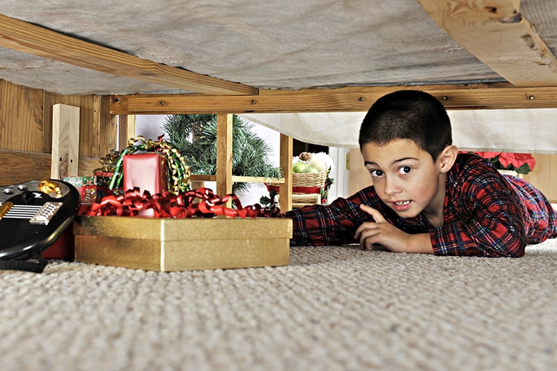 kid under bed with christmas present